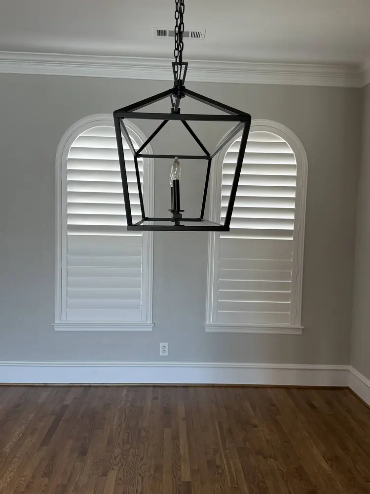 Plantation shutters on arched windows under a lantern pendant